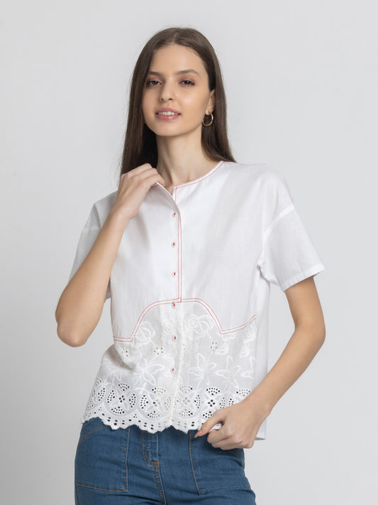 Model wearing white Cosette Shirt with round neck short sleeves button down front Schiffli embroidery hem and straight hem