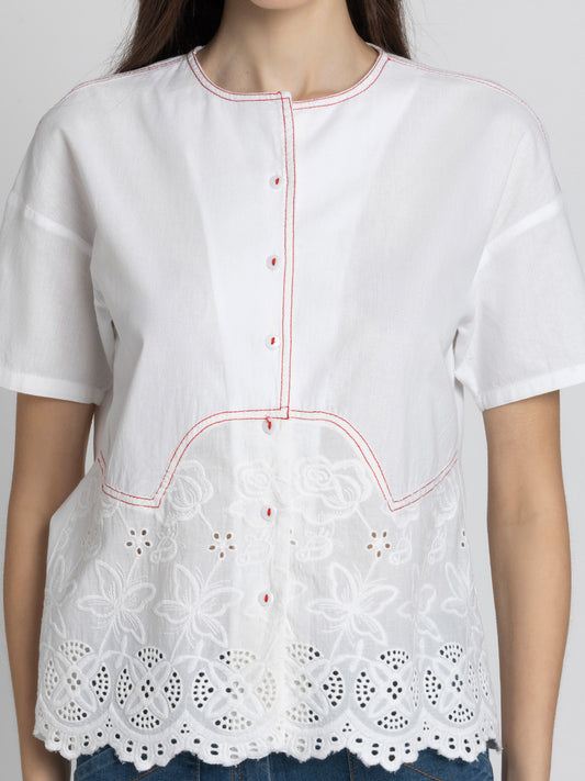 Close up of round neck and Schiffli embroidery at hem on white cotton Cosette Shirt showing soft breathable fabric