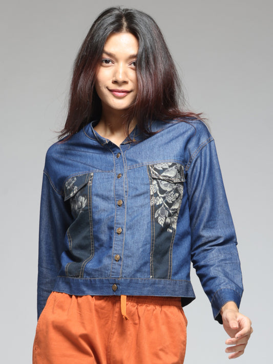 Blue denim shirt with round neck, print patch on front, full sleeves, button down, straight hemline, relaxed fit, front view