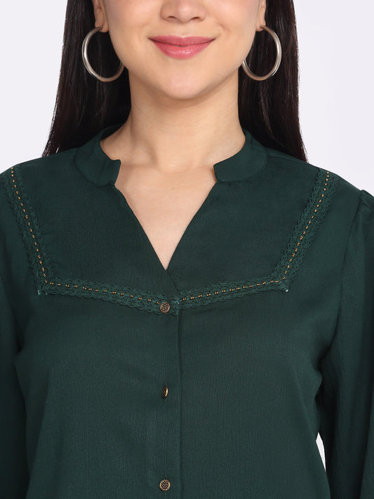 Close-up of band collar and lace yoke detail on green crinkled crepe shirt, button down front
