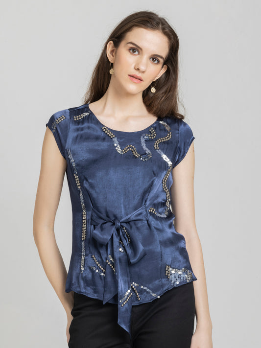 Model wearing midnight blue Vega Top with round neck short cap sleeves and front tie detail