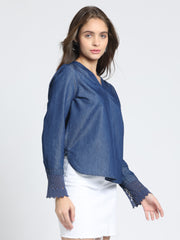 Side angle blue denim top, V-neck, relaxed fit, high-low hemline, full cuff sleeves, gathers at back yoke