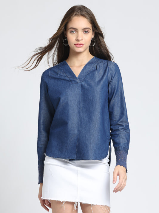 Blue denim top with V-neck, pleat detail at front, full cuff sleeves, relaxed fit, high-low hem, gathers at shoulder, front view