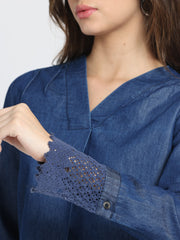 Detailed close-up of cuff sleeve, gathers, and soft denim fabric on blue V-neck high-low hem top