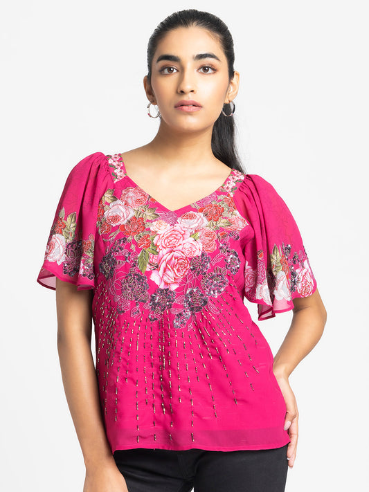 Model wearing pink Ambre Top with V-neck short flared sleeves hand embroidery on front and curved hem