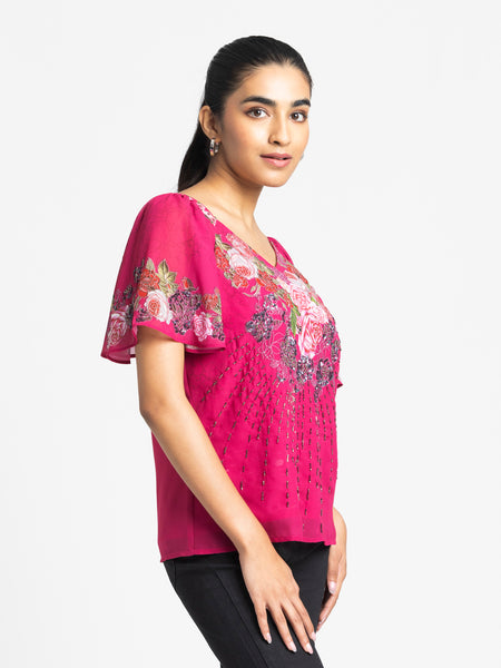 Side profile of pink printed Ambre Top with curved hem V-neck flared sleeves and hand embroidery