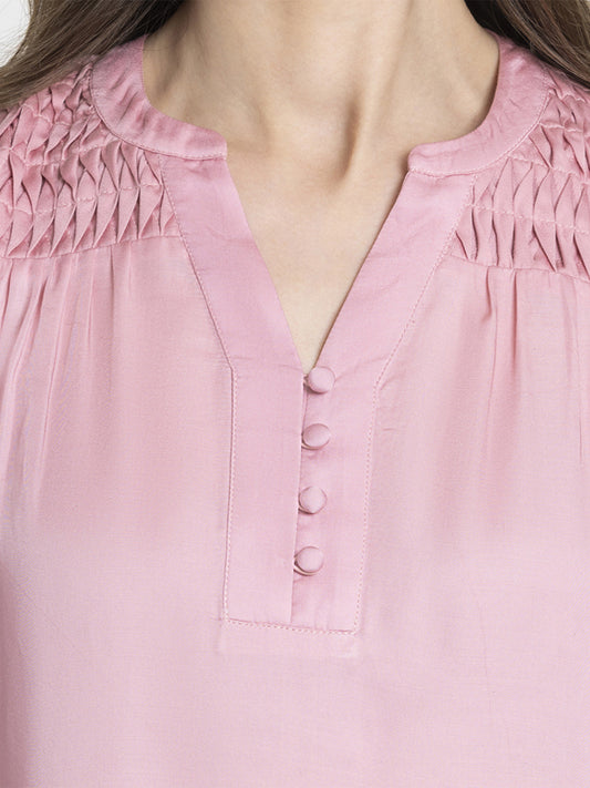 Close up of band collar V-neck with pleats detail and button closure on pink Berry Top