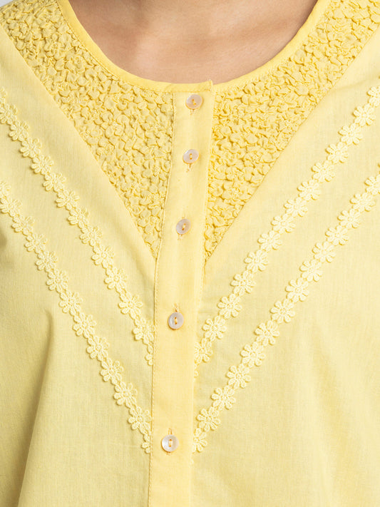 Close up of round neck embroidery on yoke and lace pintucks on front of yellow Ciara Shirt