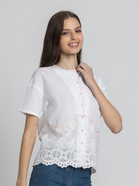 Model casually posing in white Cosette Shirt highlighting Schiffli embroidery curved hem and lightweight cotton fabric