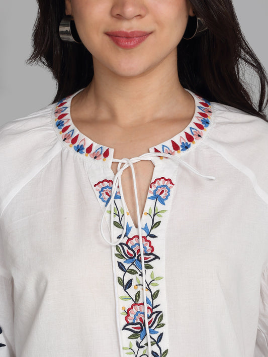 Close-up of v-neckline, floral embroidery, and tie up dori tassels on white cotton top, relaxed fit