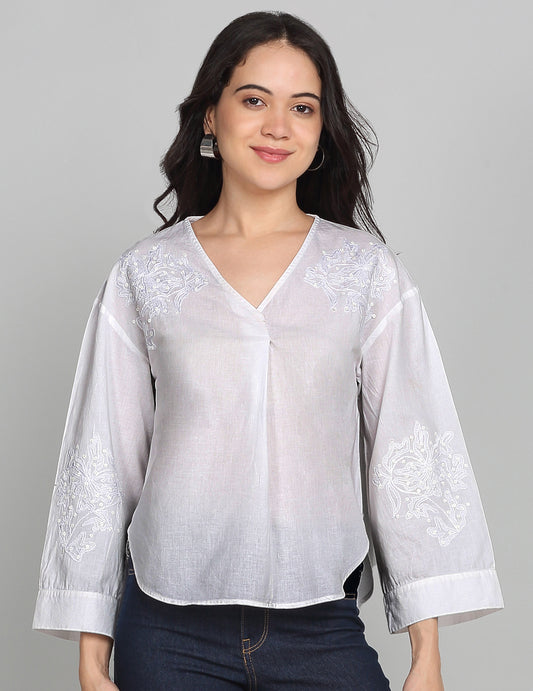 White cotton top with v-neck, three-quarter sleeves, embroidered yoke, pleats detail at front, curved hem, and relaxed fit front view