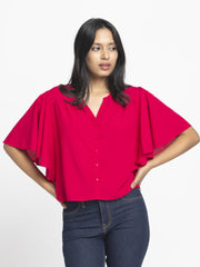 Model striking playful pose in Jacqueline Shirt highlighting short flared sleeves button down front and relax fit