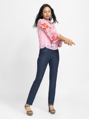 Model playfully posing in pink chiffon Maine Top with cami highlighting soft curved hem and light floral print