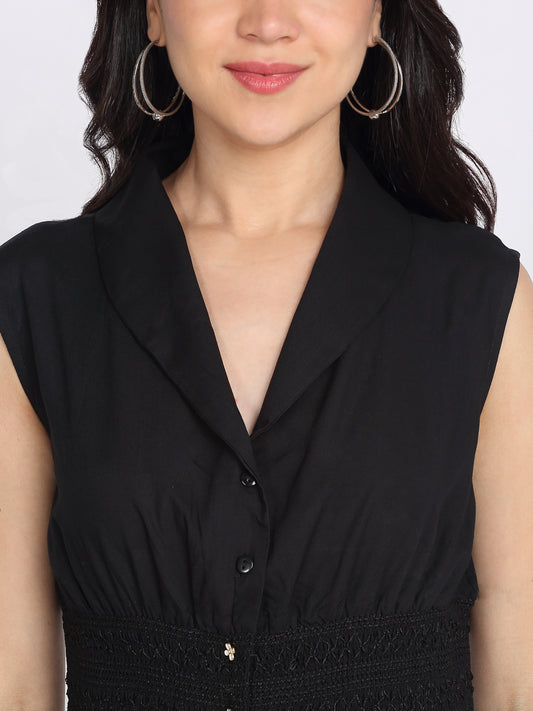 Close-up of shawl collar, button front and smocking embroidered waist on black sleeveless relaxed fit rayon dress