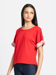 Left side view of red Thea jersey t-shirt featuring drop shoulder sleeves with floral printed detail accents