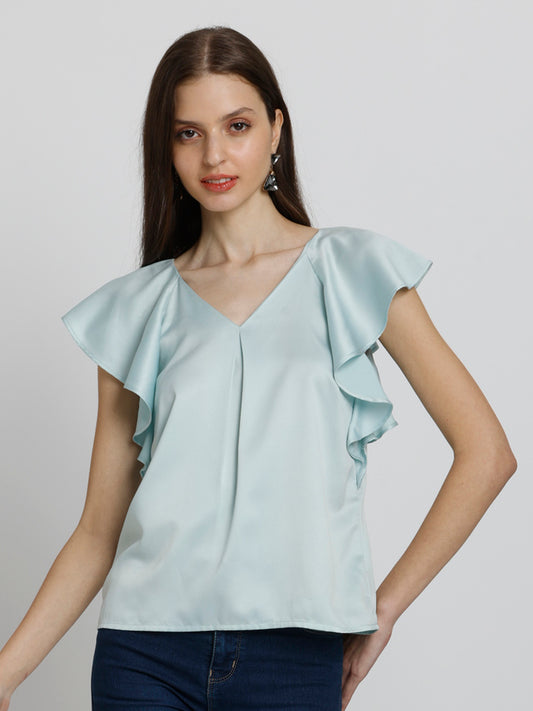 Model standing with hand on hip wearing blue Rufina Top V-neck short flared sleeves inverted pleats detail curved hem