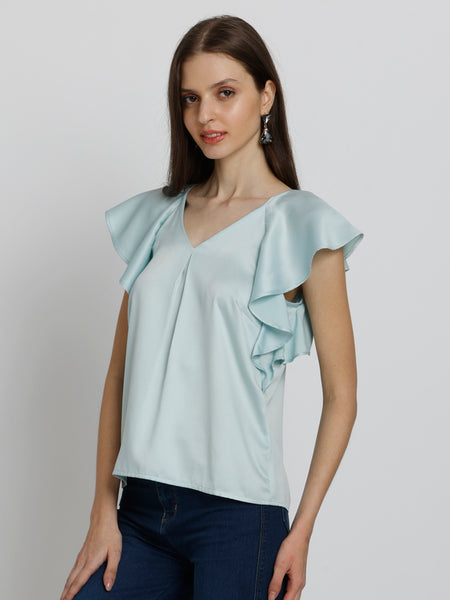 Model side pose wearing blue Rufina Top showing curved hem inverted pleats and soft flowy satin