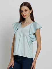 Model side pose wearing blue Rufina Top showing curved hem inverted pleats and soft flowy satin