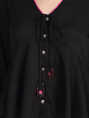 Detailed view of button front and embroidered tassels on black crinkled crepe peplum top