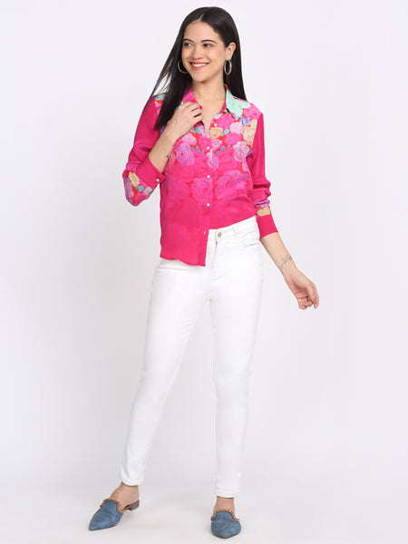 Pink floral print sheer shirt with collar, full sleeves, curved hem, lifestyle walking pose with white pants
