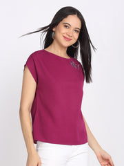 Three-quarter angle pose of purple crinkled crepe top, boat neck, floral embroidery, curved hem