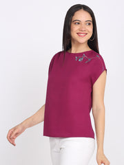 Side view of purple embroidered top boat neck, short drop shoulder sleeves, curved hem