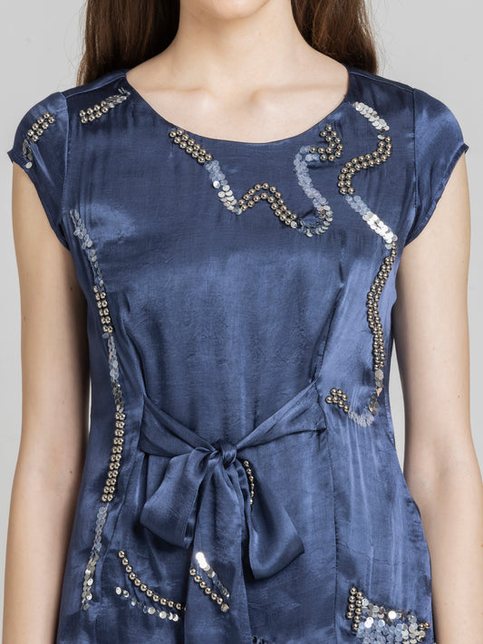 Close up of sequin embellishment on cap sleeve opening and smooth satin fabric of Vega Top