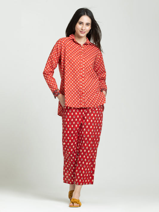 Model standing straight in red printed button down shirt with collar full cuffed sleeves and half elasticated trouser